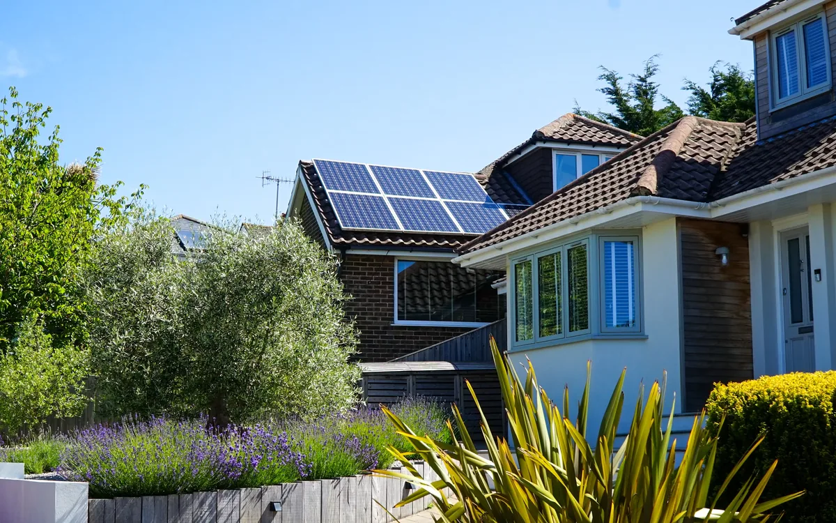 Home with rooftop solar panels under a clear blue sky